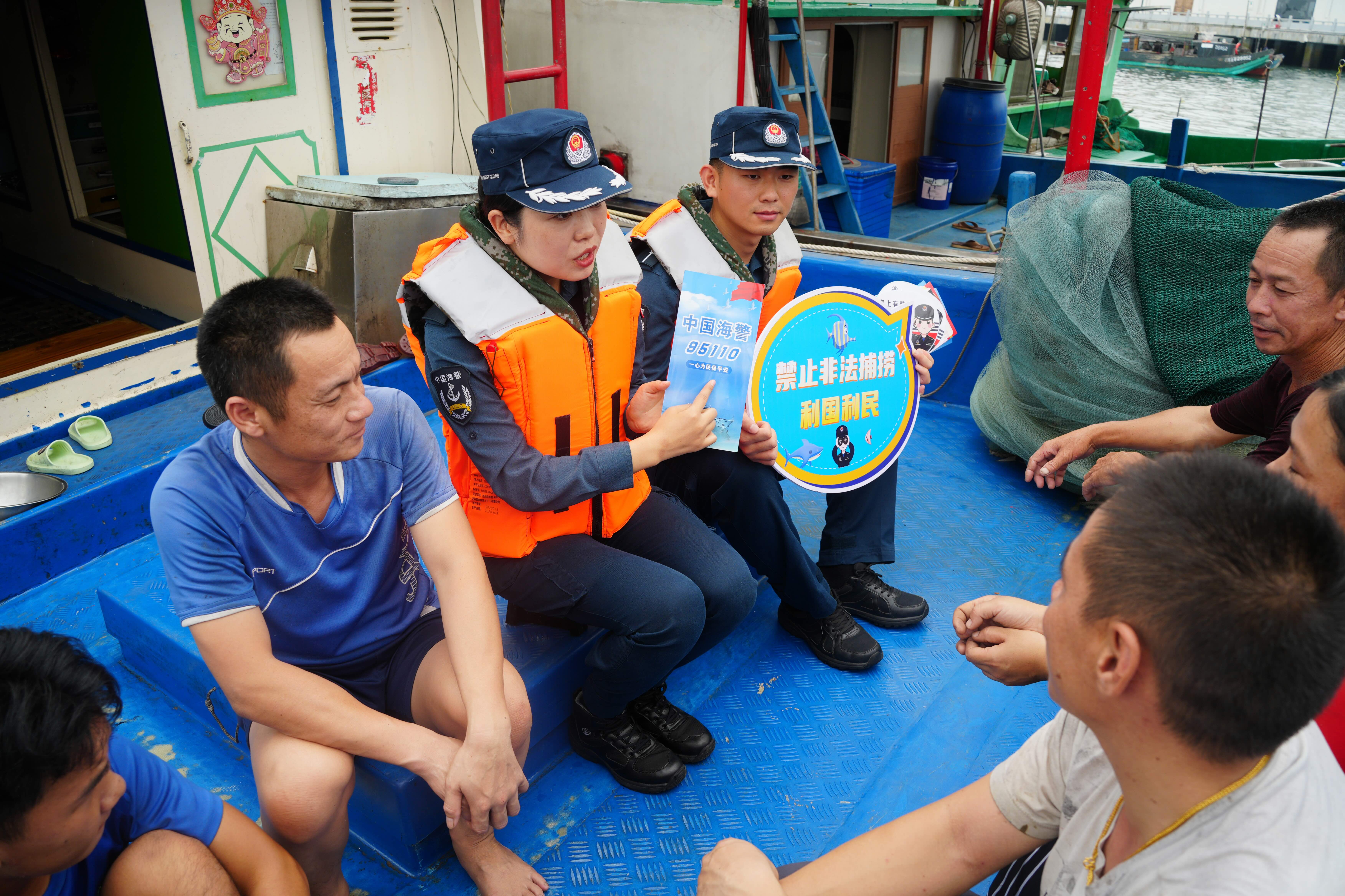 图为执法员们逐船走访，向渔民发放宣传手册和休渔政策宣传纸。 广西防城港海警局供图